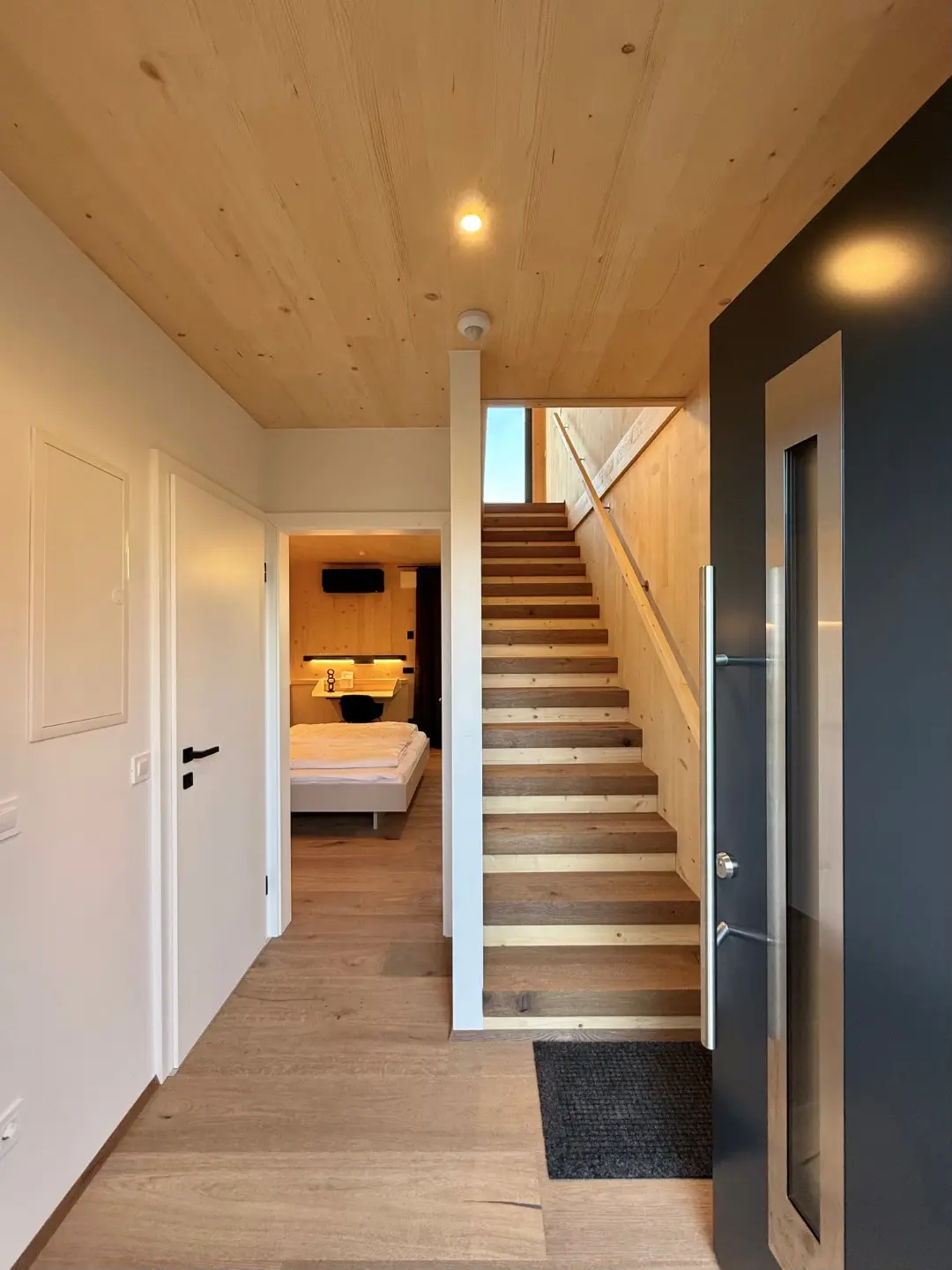 Eingangsbereich des Lofts mit offener Holztreppe und Blick ins Schlafzimmer