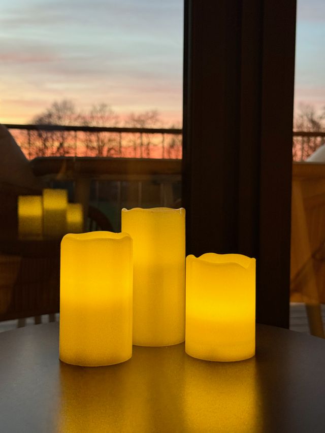 Leuchtende Kerzen vor dem Fenster bei Sonnenuntergang