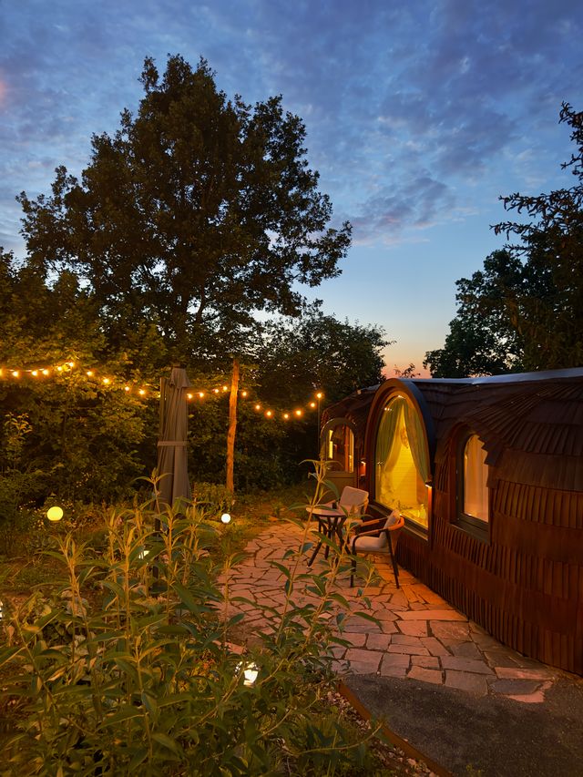 feinzeit Chalet mit Lichterkette und Terrasse in der Abenddämmerung