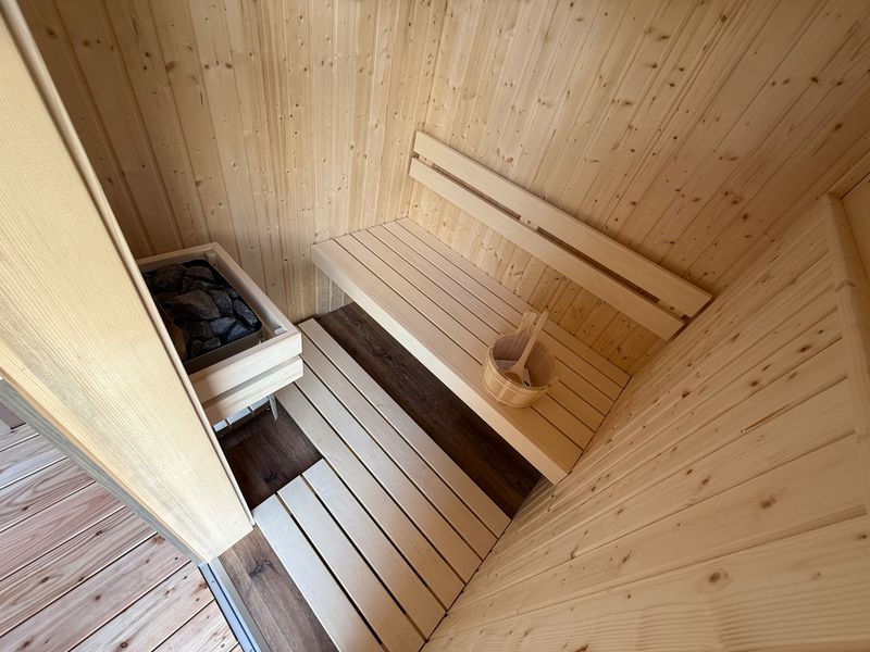 Private Sauna im Loft mit hellen Holzwänden und Saunasteinen