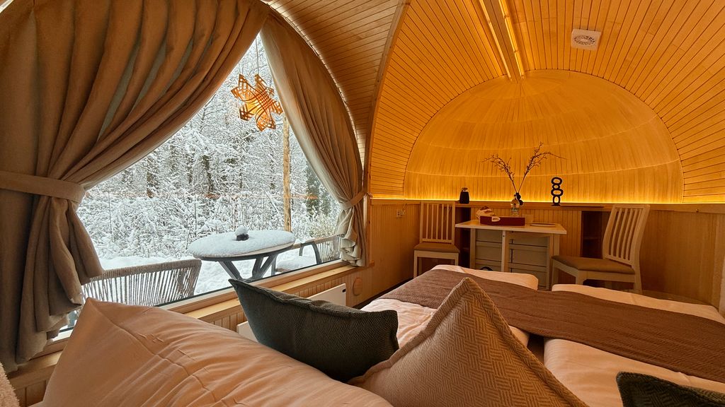 Warm beleuchtetes Chalet-Schlafzimmer mit Blick auf den verschneiten Wald